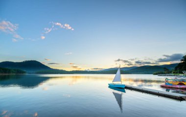 Gökyüzünden güzel günbatımında güneş yıldız ile yalnız Yelkenli parlar ve göl yüzeyine onları izlerken sakin ve huzurlu