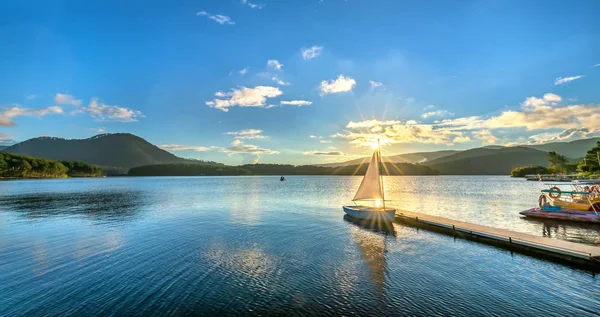 Gökyüzünden güzel günbatımında güneş yıldız ile yalnız Yelkenli parlar ve göl yüzeyine onları izlerken sakin ve huzurlu
