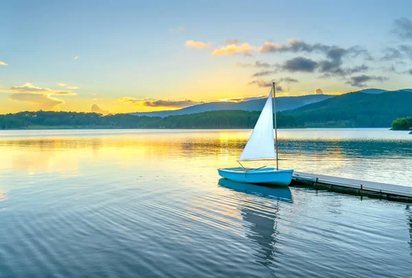 Gökyüzünden güzel günbatımında güneş yıldız ile yalnız Yelkenli parlar ve göl yüzeyine onları izlerken sakin ve huzurlu