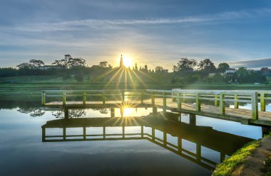 Sunrise dramatik gökyüzü ile göle bakan küçük köprüde yeni gün Vietnam turist şehir ağırlamaktadır.