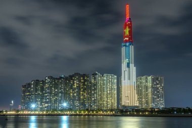 Ho Chi Minh City, Vietnam - February 4th, 2019: Colorful night scene from Landmark 81 riverside with many sparkling lights welcome lunar new year. Landmark 81 is the tallest building in Vietnam clipart