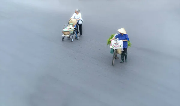 ベトナムのハノイの小さな地域で顧客を見つけるために ストリートベンダーは急いで通りを横切ってサイクリングしています — ストック写真