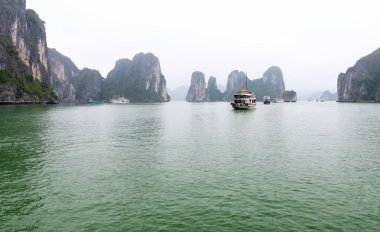 Güzel Turist yolcu gemisi Ha Long Bay kireçtaşı kayalar arasında yüzen. Burası Unesco Dünya Mirası Alanı, Kuzey Vietnam'da güzel bir doğa harikası.