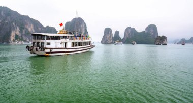 Güzel Turist yolcu gemisi Ha Long Bay kireçtaşı kayalar arasında yüzen. Burası Unesco Dünya Mirası Alanı, Kuzey Vietnam'da güzel bir doğa harikası.