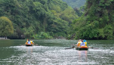 Ninh Binh, Vietnam - 5 Nisan 2019: Tam Coc Milli Parkı'nın Ngo Dong nehri üzerinde turist taşımak için tekne kürek kullanan insanlar. Tam Coc Ninh Binh, Vietnam popüler bir turistik yer.