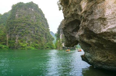 Ninh Binh, Vietnam - 5 Nisan 2019: Tam Coc Milli Parkı'nın Ngo Dong nehri üzerinde turist taşımak için tekne kürek kullanan insanlar. Tam Coc Ninh Binh, Vietnam popüler bir turistik yer.