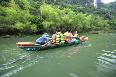 Ninh Binh, Vietnam - 5 Nisan 2019: Tam Coc Milli Parkı'nın Ngo Dong nehri üzerinde turist taşımak için tekne kürek kullanan insanlar. Tam Coc Ninh Binh, Vietnam popüler bir turistik yer.