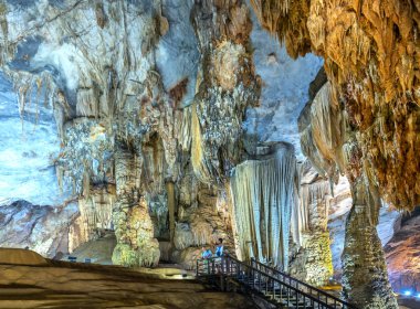 Ninh Binh, Vietnam - 7 Nisan 2019: Phong Nha milli parkında sarkıt ve dikitler ile doğal doğal koridor Paradise Cave ile ahşap geçit üzerinde turistler ziyaret, Quang Binh, Vietnam
