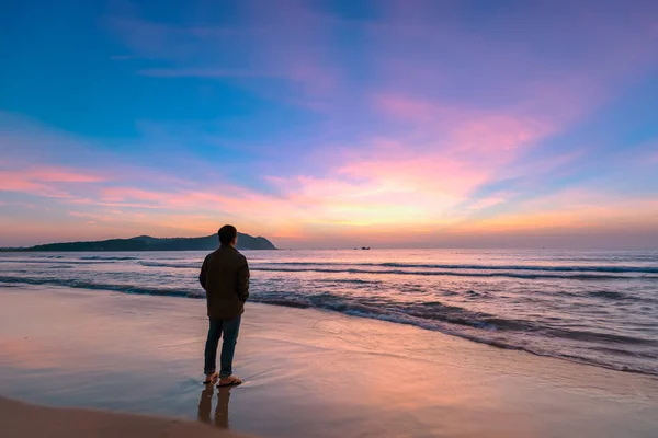 Silhouette of man on the beach looking at magical dramatic sunrise. The man standing on the sandy beach