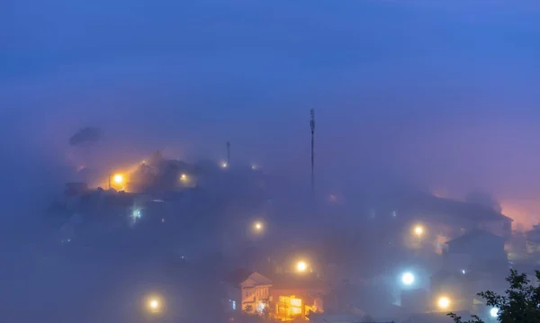 The city sunk in the night fog with bright electric lights in the mist creating a fanciful, impressive scene in Da Lat, Vietnam