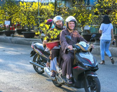Ho Chi Minh City, Vietnam - 2 Şubat 2019: Ho Chi Minh, Vietnam'da Ay yeni yıl için dekorasyon amaçlı ev arkasında insanlar sahibi kayısı saksı ile bir motosiklet sürüş genç bir Vietnamlı