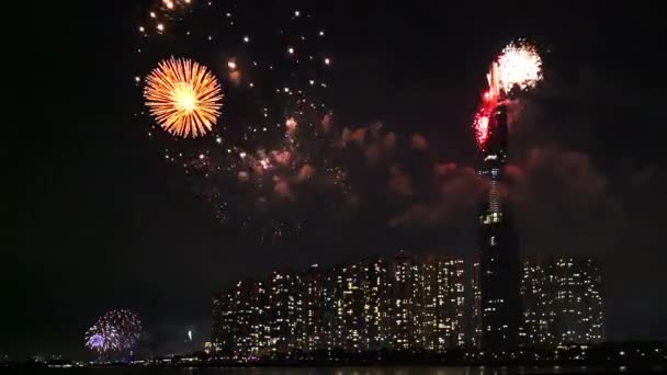ベトナムホーチミン市 2019年2月4日 ベトナムのホーチミン市で新年を迎える川沿いの都市エリアの超高層ビルの横で夜に輝く空のカラフルな花火 — ストック動画