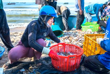 Phan Thiet, Vietnam - 12 Temmuz 2020: Deniz ürünleri pazarı oturumu denizleri, insanlar yengeçlerin, salyangozların ve balıkların içinde toplanıyor, kürek çeken balıkçı balıkları Phan Thiet, Vietnam 'daki balıkçı köyüne getirildi.