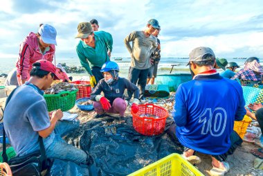 Phan Thiet, Vietnam - 12 Temmuz 2020: Deniz ürünleri pazarı oturumu denizleri, insanlar yengeçlerin, salyangozların ve balıkların içinde toplanıyor, kürek çeken balıkçı balıkları Phan Thiet, Vietnam 'daki balıkçı köyüne getirildi.