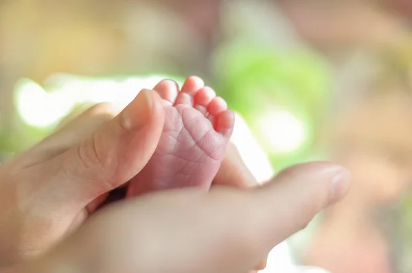 Baby s fötter närbild bild. Mor s händer som håller barn s fot. Liten flicka s fingrar framtill. — Stockfoto