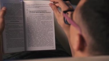 Zor bir günün ardından yatakta kitap okuyan genç bir adam