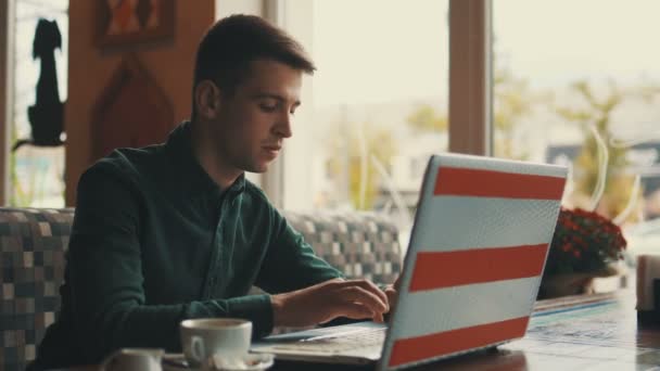 Avlägsen bild av en ung affärsman sitter vid ett bord på ett kafé, titta förbipasserande. Framgångsrika människor, dagliga rutiner. Underhållande, avslappnande, chatta. — Stockvideo