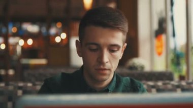 Düşünceli genç işadamı bir kafede bir masada oturuyor, bir dizüstü bilgisayar içine bakıyor ve yoldan geçenler izliyor. Başarılı insanlar, günlük rutin. Eğlenceli, dinlendirici, sohbet eden.