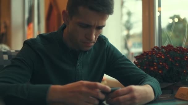 Невпізнаваний чоловік сидить в ресторані і використовує смартфон . — стокове відео