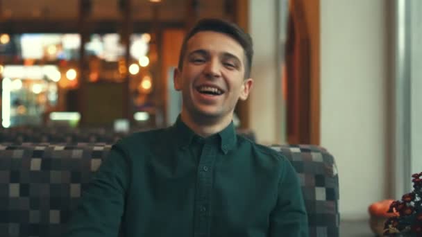 Happy attractive young man looking at the camera and smiling in a cafe — Stock Video