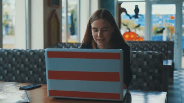 Hermosa mujer de negocios que trabaja detrás de un ordenador portátil en un café y esperando café — Vídeos de Stock