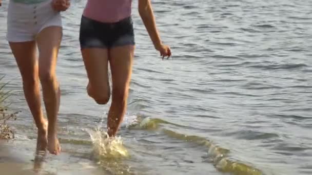 Två vackra modeller som löper längs stranden av en strand — Stockvideo