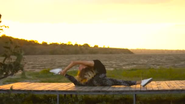 Junge Frau im Body praktiziert Yoga am Strand über dem Meer bei herrlichem Sonnenaufgang — Stockvideo