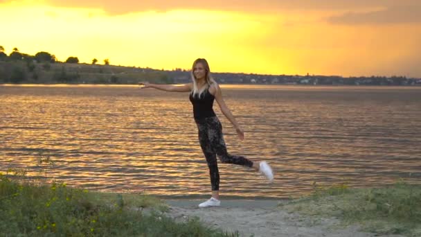 Jonge vrouw in Romper beoefenen van yoga op het strand boven zee bij verbazingwekkende zonsopgang — Stockvideo