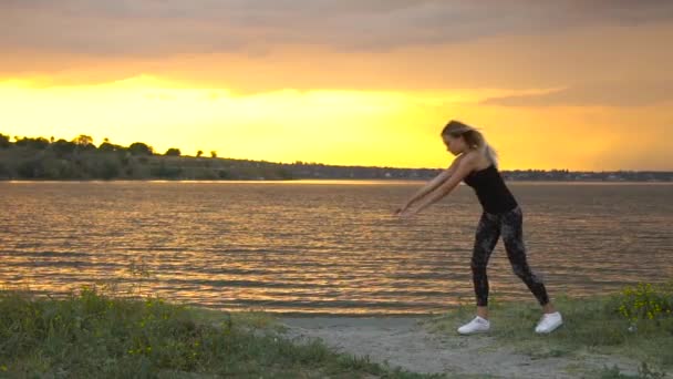 Mladá žena v obleku cvičila jóga na pláži nad mořem v úžasným východu slunce
