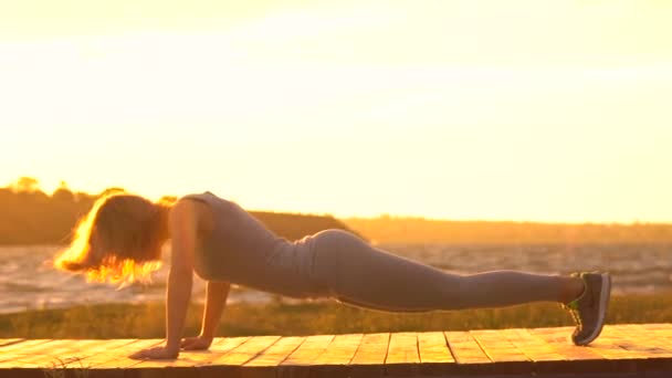 Junge Frau im Body praktiziert Yoga am Strand über dem Meer bei herrlichem Sonnenaufgang — Stockvideo