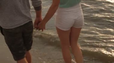 Bir çift şarap içiyor ve gün batımında sahilde yürüyor.