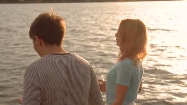 Una pareja bebiendo vino y caminando por la playa al atardecer — Vídeos de Stock