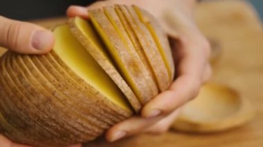 Patates kesmek. Kadın eli patatesleri, patates dilimlerini yakın plan bir mutfak tahtasında tutuyor..