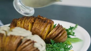 Fırında patates sosu. Tabakta dilimlenmiş patates. Soslu sağlıklı fırında patates.