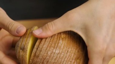 Patates kesmek. Kadın elleri patatesleri, patates dilimlerini ahşap mutfak tahtasına yakın çekimde tutuyor.