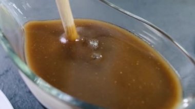 Tatlı şurup, bal sosu ya da sopayla karıştırılır. Kavanozda kahverengi sıvıyla bal çubuğu