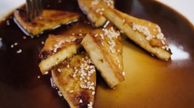 Lezzetli üçgen peynirli kekler tabakta şerbetli. Çatalla tatlı şuruba batırılmış peynirli kekler. Güzel servis..