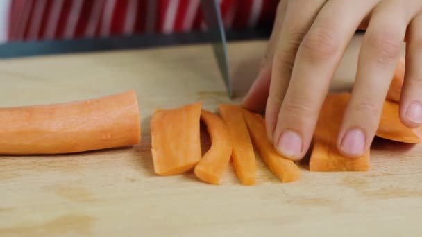 Chef cuts carrot. Cooking process. Hands cutting carrot. Womans hands slice the carrot — Stock Video