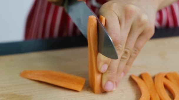 Woman slices the carrot on long pieces. Cooking process. Chef cuts the carrot. — Stock Video