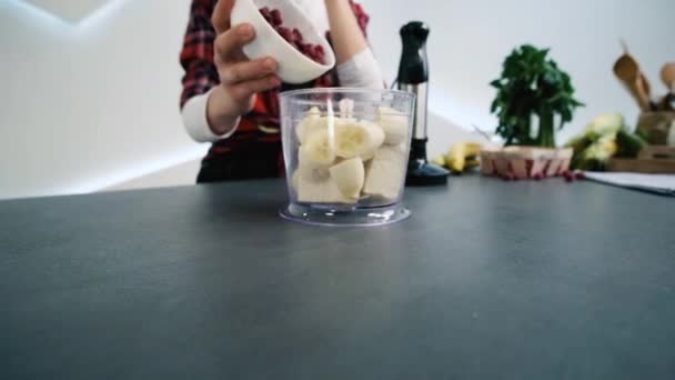 La mujer pone la frambuesa en el plato de la licuadora con el plátano. Hacer batido saludable . — Vídeos de Stock