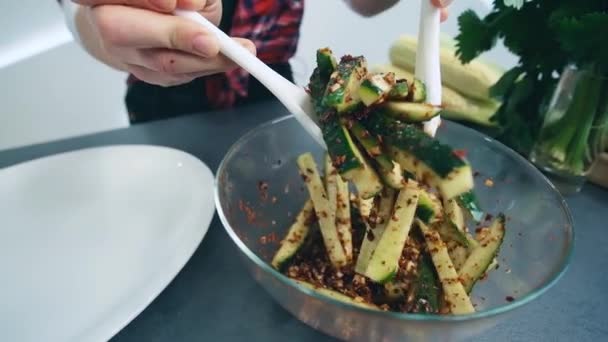 A nő vesz uborkát fűszerekkel a tálból, és egy tányérra teszi. Fűszeres uborkát szeletelt. Egészséges főzés. — Stock videók