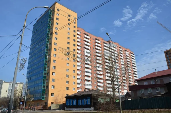 Bu resim yeni bir bina eski bir ahşap ev gösteriyor.