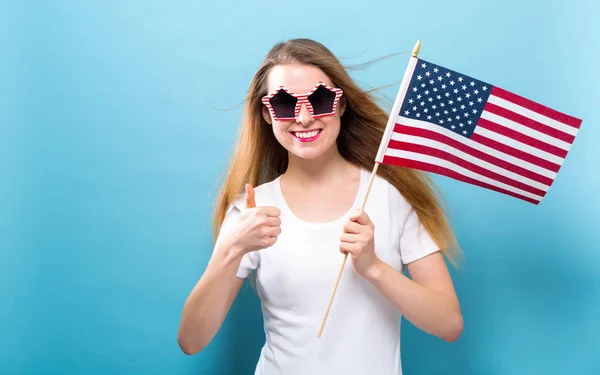 Happy young woman holding an American flag — Stock Photo, Image