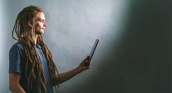 Jovem usando um tablet em um fundo escuro — Fotografia de Stock