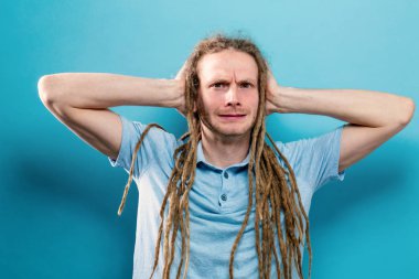 Genç adam sağlam bir arka plan üzerinde kulakları engelleme