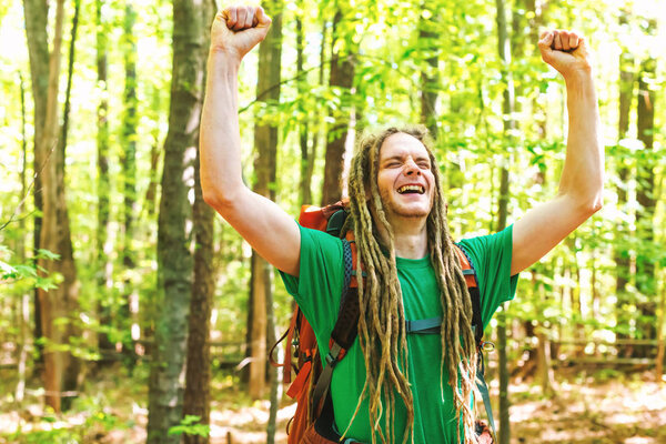 Happy hiker raising his hands in the air in a victory salute in the forest