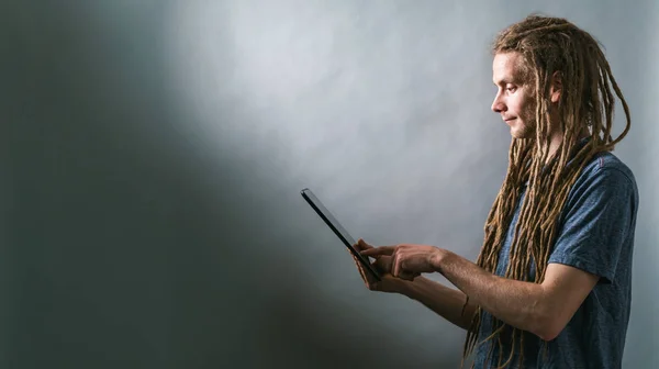 Jeune homme utilisant une tablette sur un fond sombre — Photo