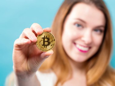 Fiziksel bir bitcoin tutan kadın