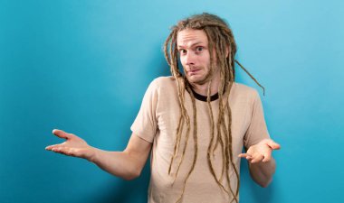 Genç adam sağlam bir arka plan üzerinde shrugging