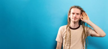 Genç adam sağlam bir arka plan üzerinde dinleme